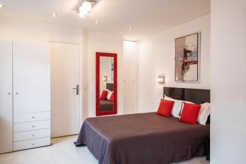 a bedroom with a bed with red pillows and a mirror at Hotel De L'Horloge in Paris
