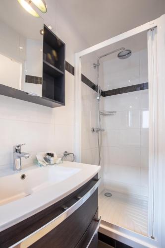 a white bathroom with a shower and a sink at Hotel De L'Horloge in Paris