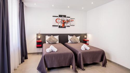 a bedroom with two beds with pillows on them at Hotel De L'Horloge in Paris