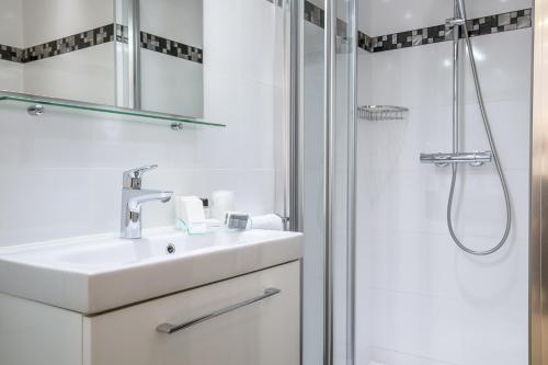 a white bathroom with a sink and a shower at Hotel De L'Horloge in Paris