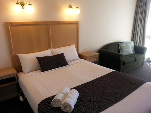 a hotel room with a bed and a chair at Big Valley Lakeside Paradise Motor Inn in Shepparton