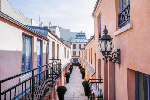 an alleyway between two buildings with a balcony at Hotel De L'Horloge in Paris