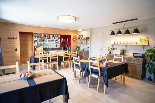 a restaurant with tables and chairs and a kitchen at Le jardin des 4 saisons in Le Mans