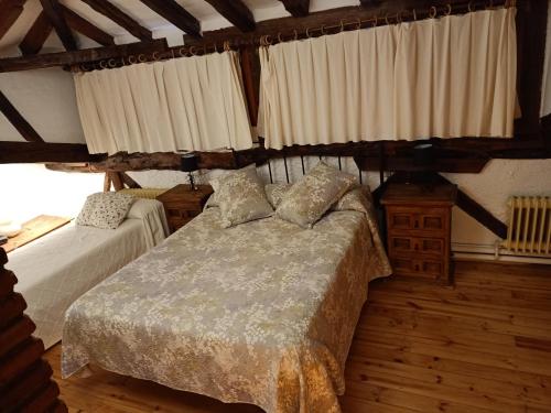 a bedroom with two beds in a room with wooden floors at casa rural decerca in Arcones