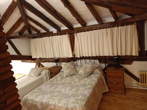 1 dormitorio con 2 camas en una habitación con techos de madera en casa rural decerca, en Arcones