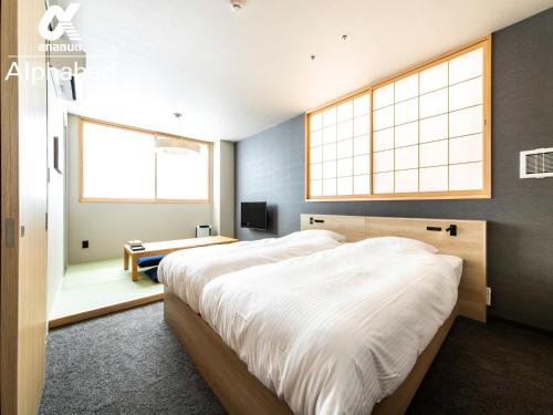 1 dormitorio con 1 cama grande y 2 ventanas en ALPHABED INN Fukuoka Ohori Park - Vacation STAY 06391v en Fukuoka