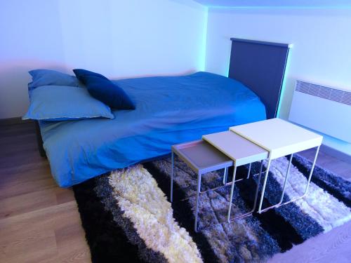- un lit avec une couette bleue et 2 tables dans l'établissement Grand studio, Ramblas de Toulouse, Jean Jaurès, à Toulouse