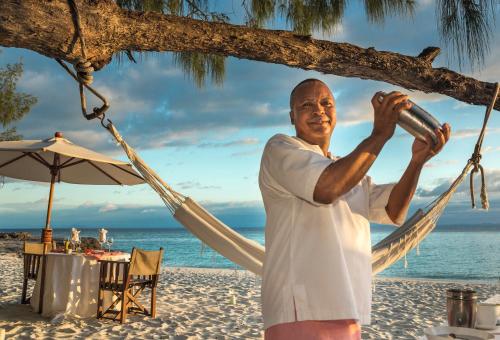 a man standing in a hammock on the beach at Constance Tsarabanjina - All Inclusive in Nosy Mitsio