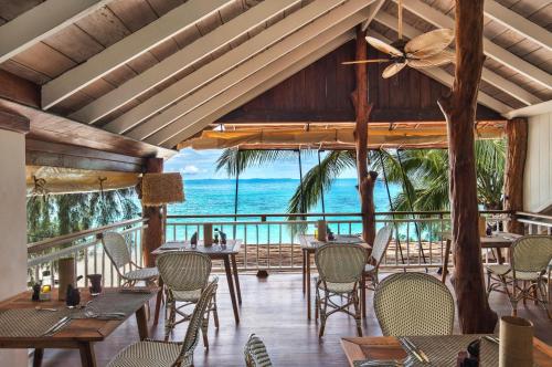 a restaurant with tables and chairs and a view of the ocean at Constance Tsarabanjina - All Inclusive in Nosy Mitsio