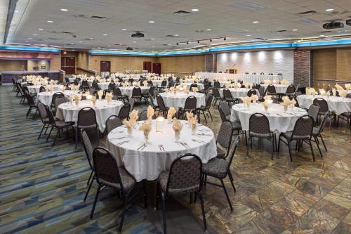 un salón de banquetes con mesas y sillas blancas en Grand Hotel en Minot