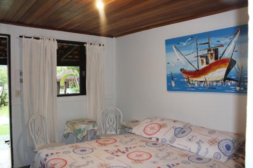 a bedroom with a bed and a painting of a boat at Pousada Canto da Galheta in Ilha do Mel