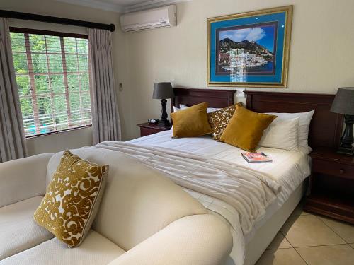 a bedroom with a white bed and a couch at Gallo Manor Executive Bed & Breakfast in Johannesburg