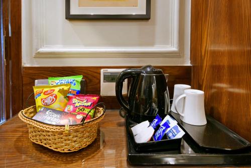 a cup of coffee sitting on a counter next to a bag of cookies at Hotel Blue Pearl in New Delhi