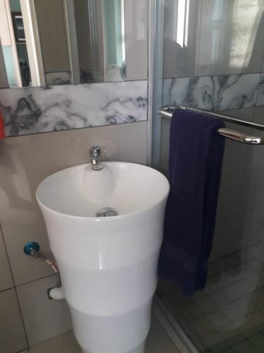 a white toilet in a bathroom with a blue towel at Masane Lodge in Rustenburg