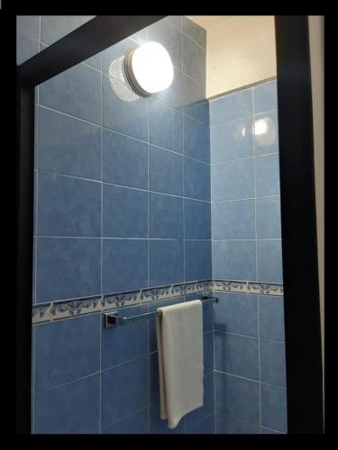 a blue tiled bathroom with a towel and a light at CIUDAD DE MEXICO UNAM Guest House Casa de Huespedes in Mexico City