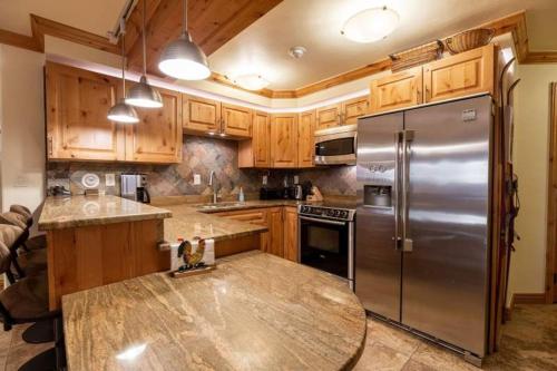 una cocina con nevera de acero inoxidable y armarios de madera en Nine Vail Road Professionally Managed, en Vail