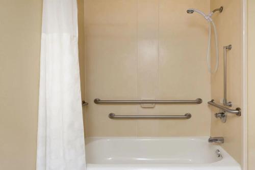 a bathroom with a bath tub with a shower curtain at Ramada by Wyndham Locust Grove in Locust Grove