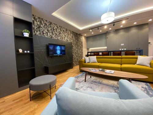 a living room with a yellow couch and a table at Stone Lux Apartman in Subotica