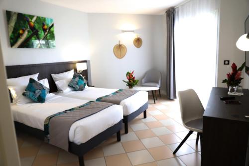 a hotel room with two beds and a desk at Hôtel Saint-Georges in Saint-Claude
