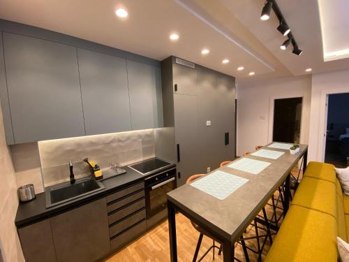 a kitchen with a table and a sink and a counter at Stone Lux Apartman in Subotica