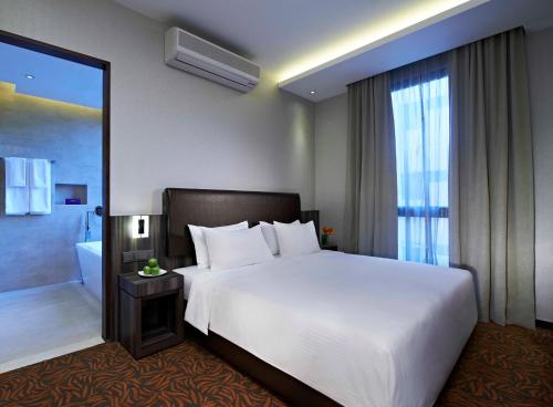 a bedroom with a large white bed and a bathroom at Aqueen Hotel Kitchener in Singapore