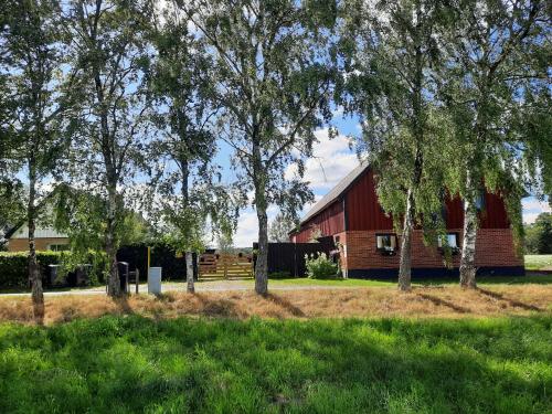 a red barn with trees in front of it at Rya B & -B Tollarp lägenhetsboende in Tollarp