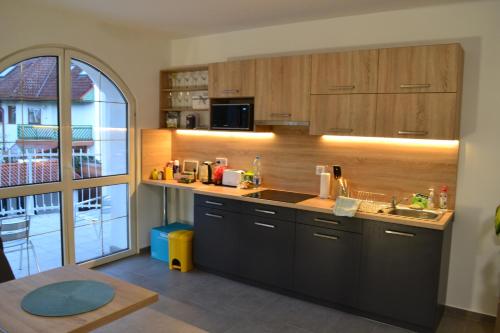 a kitchen with wooden cabinets and a large window at Főnix Design Rooms in Debrecen