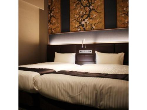 two beds in a hotel room with a painting on the wall at Hotel Halrotto Fukuoka Hakata - Vacation STAY 04193v in Fukuoka