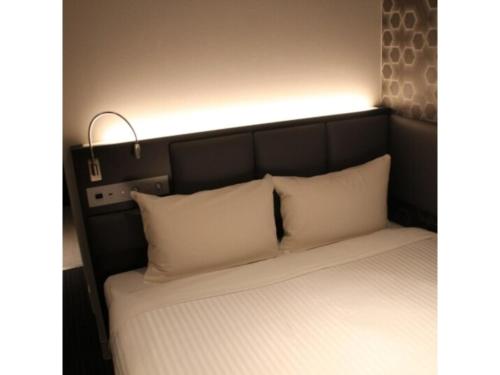 a bed with white pillows and a light above it at Hotel Halrotto Fukuoka Hakata - Vacation STAY 04185v in Fukuoka