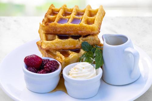 a plate with a waffle and berries and a cup of coffee at Holiday Inn Auckland Airport, an IHG Hotel in Auckland