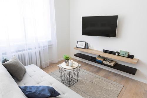 Una sala de estar con un sofá blanco y un televisor de pantalla plana. en Flower Square Apartments, en Zagreb
