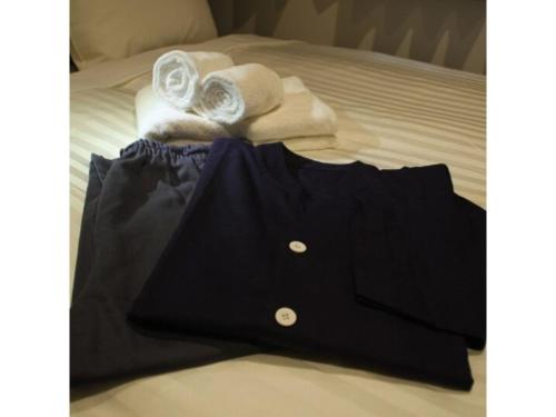 une chemise noire et des serviettes sur un lit dans l'établissement Hotel Hulaton Fukuokahakata - Vacation STAY 04196v, à Fukuoka