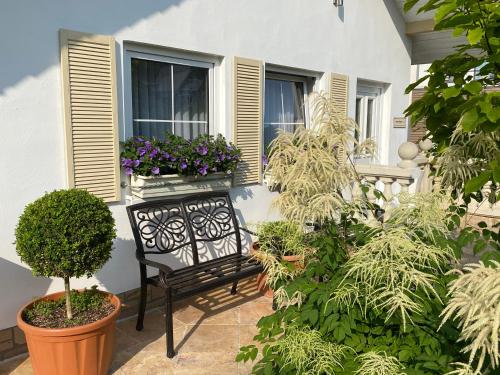 a black bench sitting on a porch with plants at Wilsmann Apartmentvermietung in Hövelhof