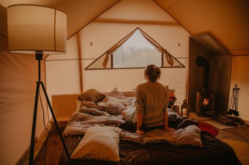 a woman sitting on a bed in a room at Torma Puhkemaja ja Glämping in Torma