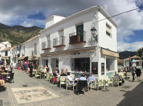 a group of people sitting at tables outside a building at Sea to Sky Suites - Mijas Pueblo in Mijas