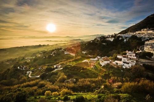 a village on a hill with the sun in the sky at Sea to Sky Suites - Mijas Pueblo in Mijas