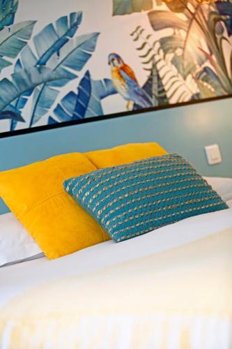 a bed with a yellow pillow and a picture at Le Saint Erasme, Hotel Eco Friendly in Calvi