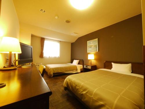 a hotel room with two beds and a flat screen tv at Hotel Route-Inn Ageo in Ageo