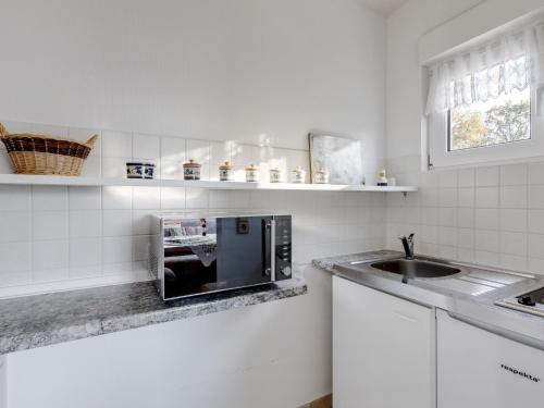 cocina blanca con microondas y fregadero en Cozy Bungalow in Werder with Garden en Petzow