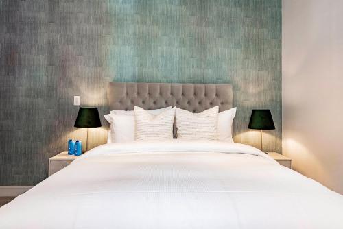 a bedroom with a large white bed with two lamps at Mayfair Magic in London