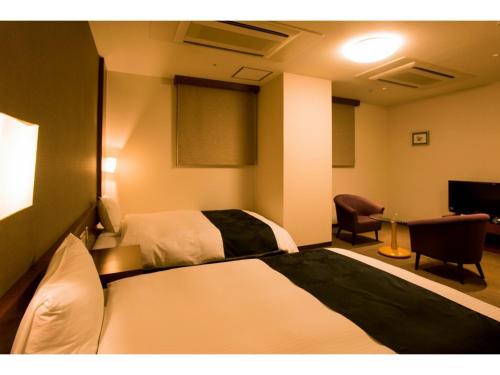 鹿児島市にあるHotel Taisei Annex - Vacation STAY 05213vのベッドと椅子のあるホテルの部屋