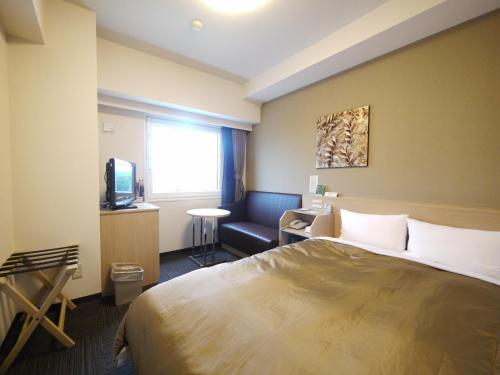Habitación de hotel con cama, silla y TV en Hotel Route-Inn Sendai Taiwa Inter, en Taiwa