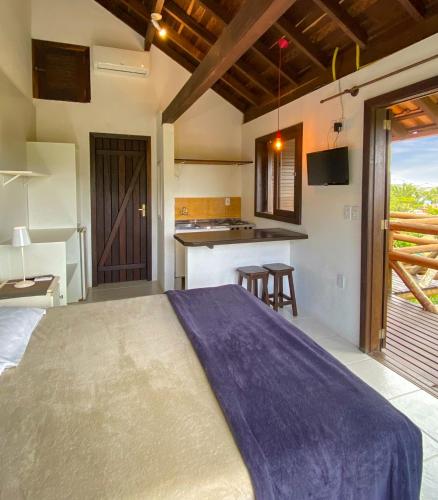 a bedroom with a large bed and a kitchen at Pueblo Rosa Norte in Praia do Rosa