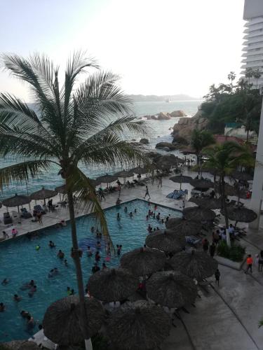 a group of people in a swimming pool with umbrellas at Hermosa Suite Torres Gemelas in Acapulco