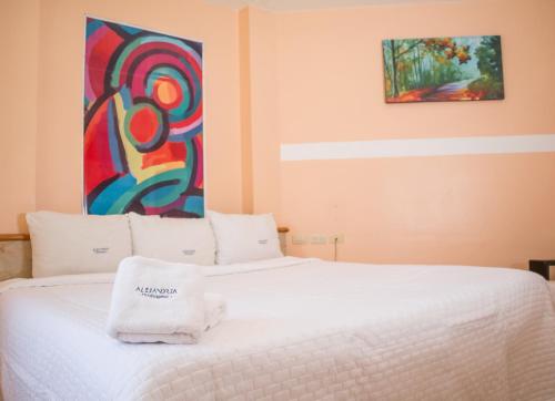 a bedroom with a white bed with a painting on the wall at Hotel Express Alejandría in Xalapa