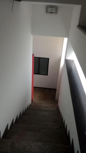 pasillo con escalera en un edificio blanco con puerta roja en Depa Kava II, en Miranda