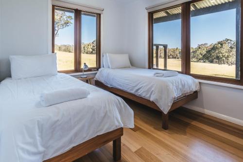 a bedroom with two beds and two windows at Worrowing Jervis Bay in Huskisson