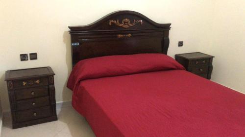 - une chambre avec un lit rouge et 2 tables de chevet dans l'établissement شقق مفروشة للايجار, à Ksar Sghir
