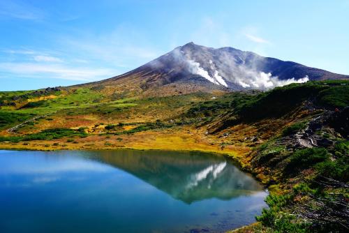 a mountain with a lake in front of it at Tabist THE GREEN ASAHIKAWA in Asahikawa
