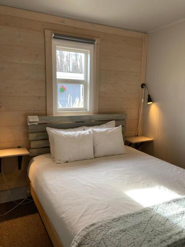 1 dormitorio con 1 cama blanca y ventana en Pinewood Inn, en Golden